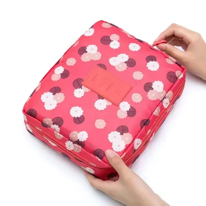 Floral-patterned pink storage bag with a hand holding it on a white background